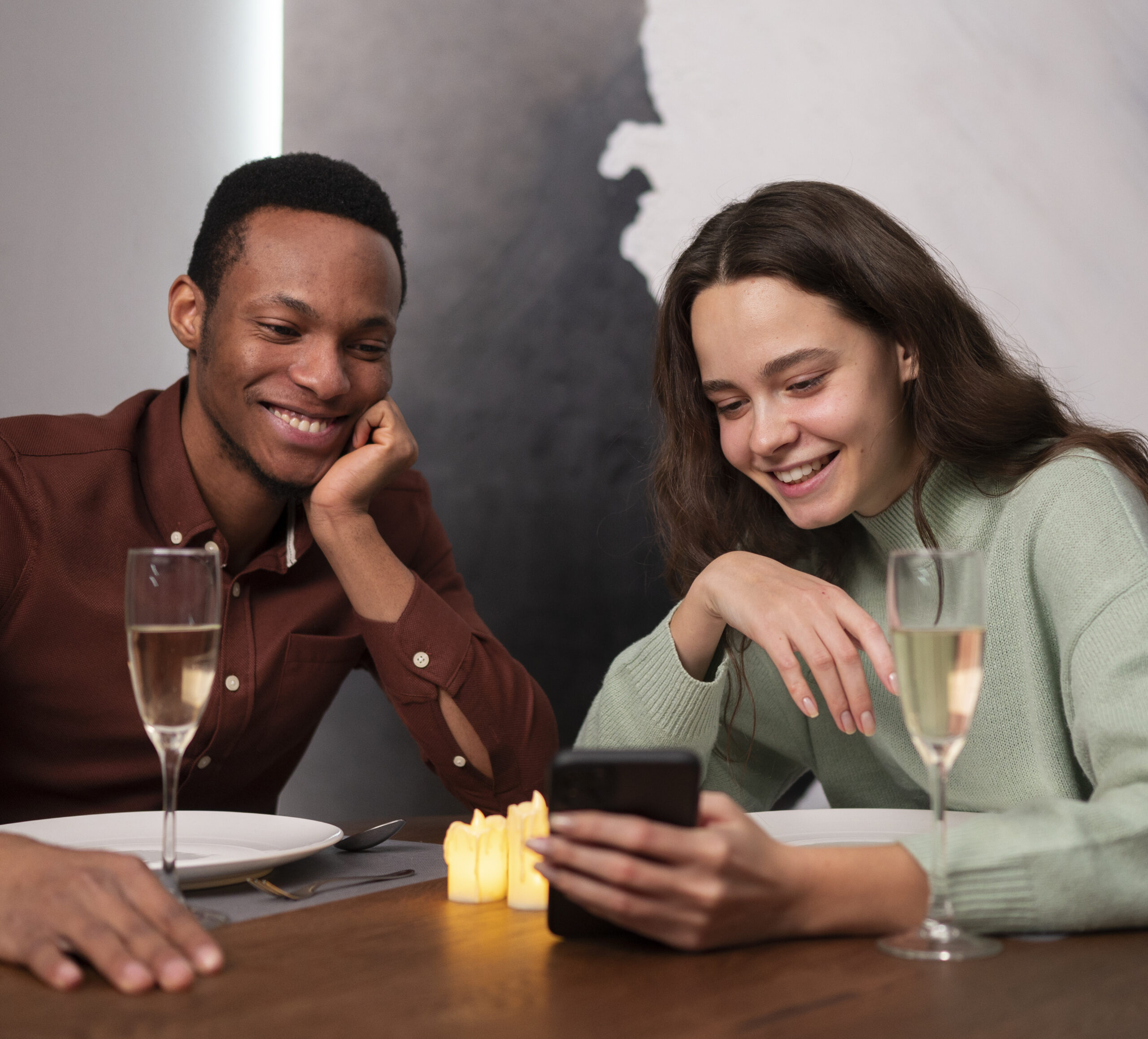 Couple en rendez-vous dans un restaurant à Angers regardant un téléphone